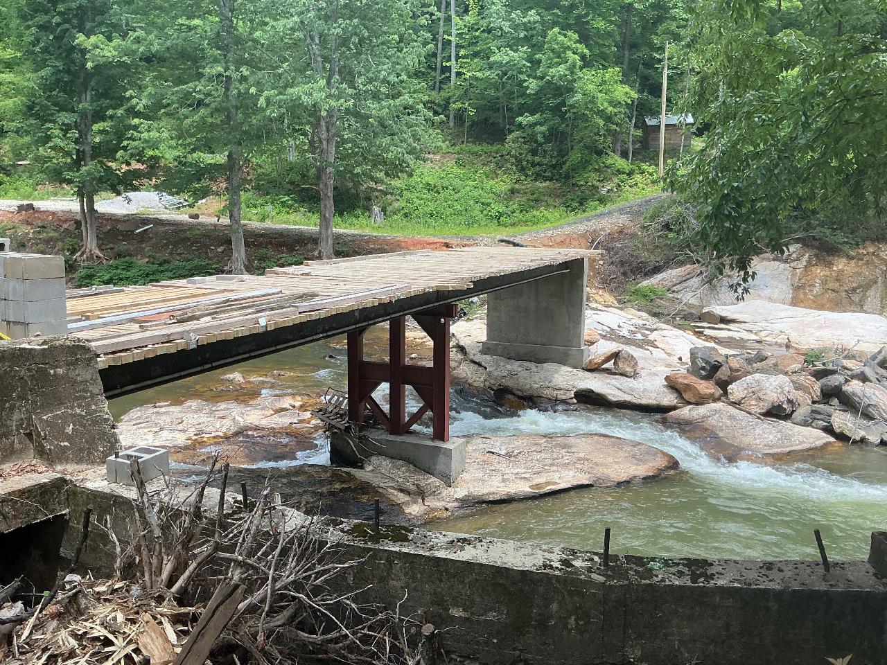 Wooden bridge over a rocky stream surrounded by lush greenery
