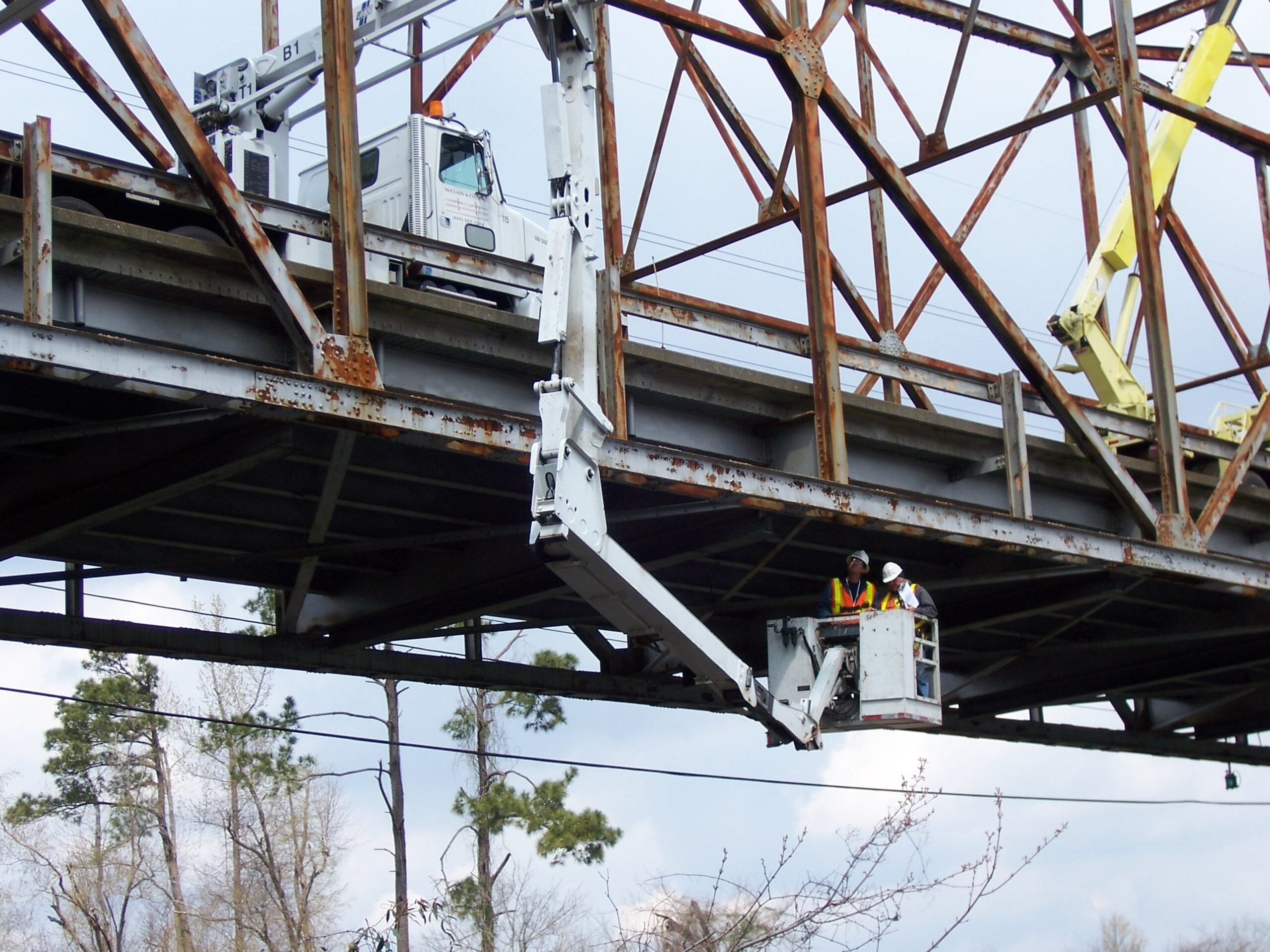 Workers inspecting bridge underside using hydraulic lift platform