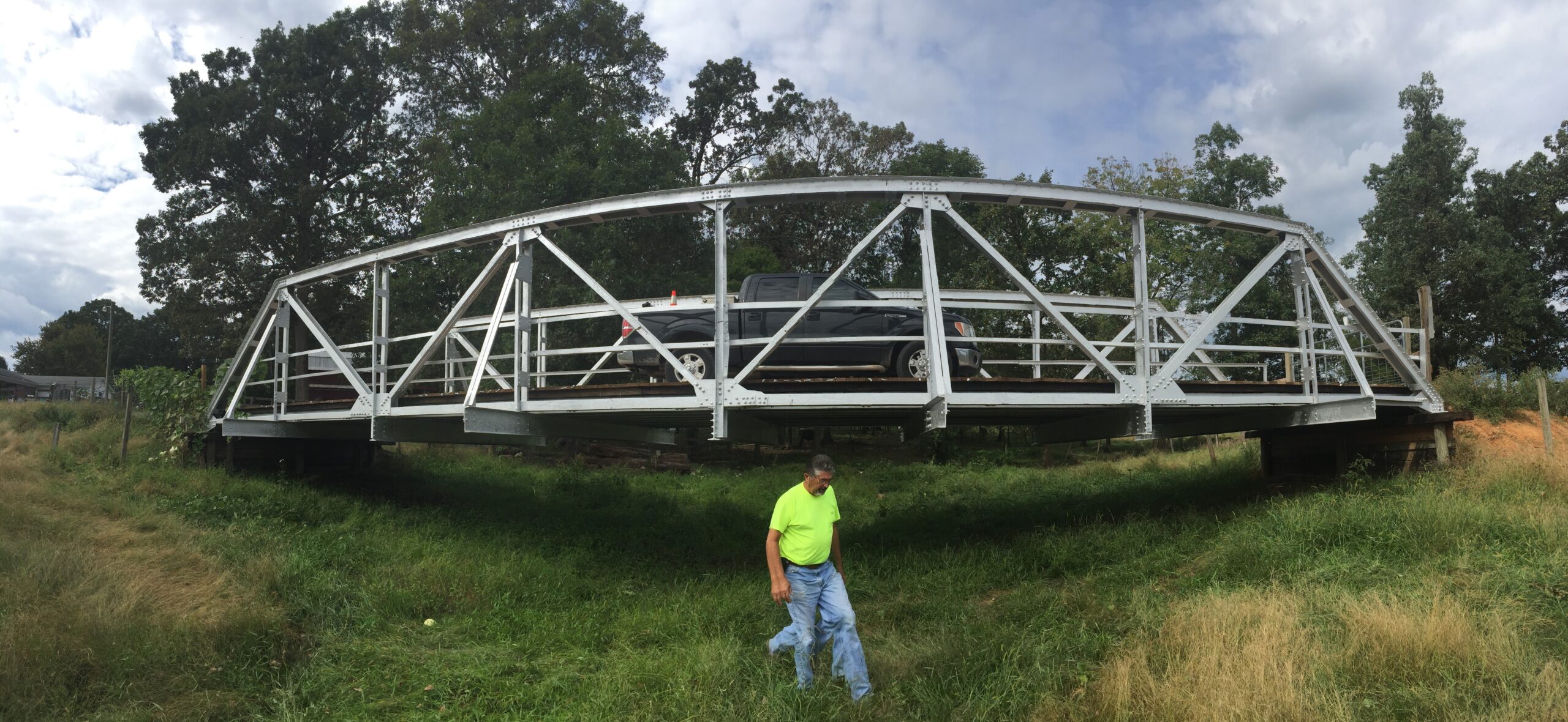 Steel bridge with a parked truck; man in bright shirt walking below
