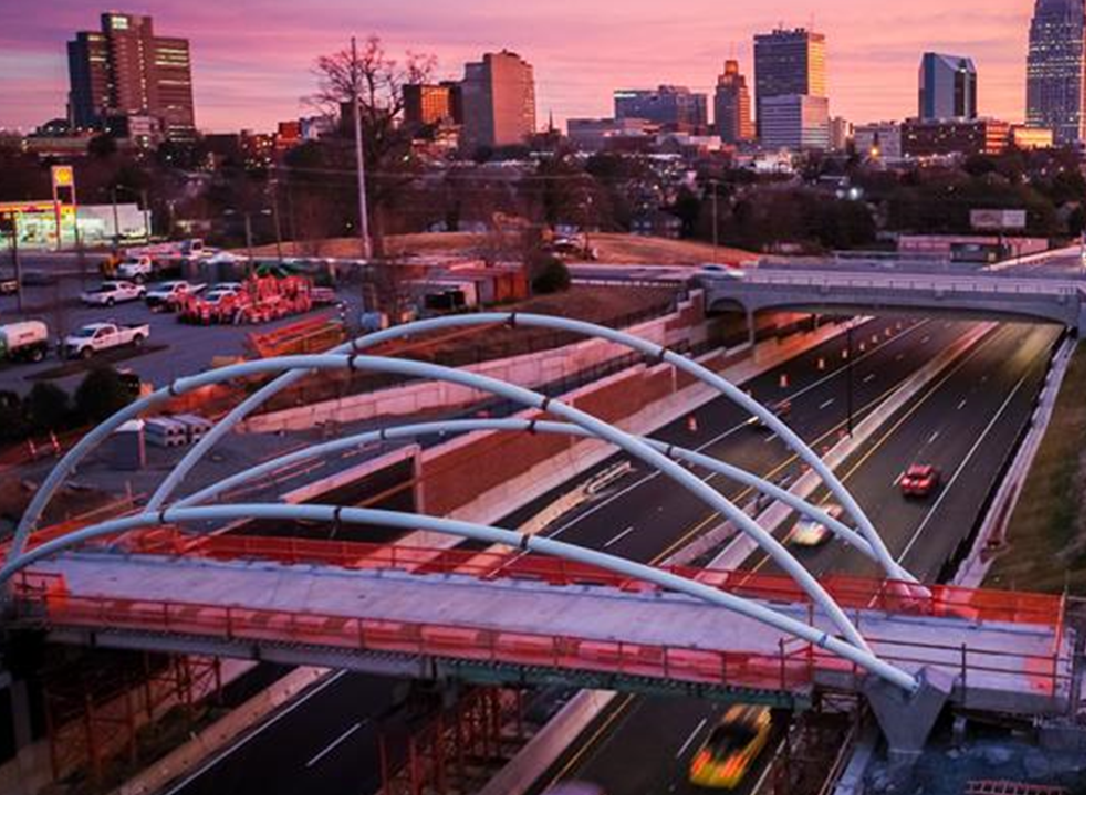 Urban skyline at sunset with a pedestrian bridge over a highway