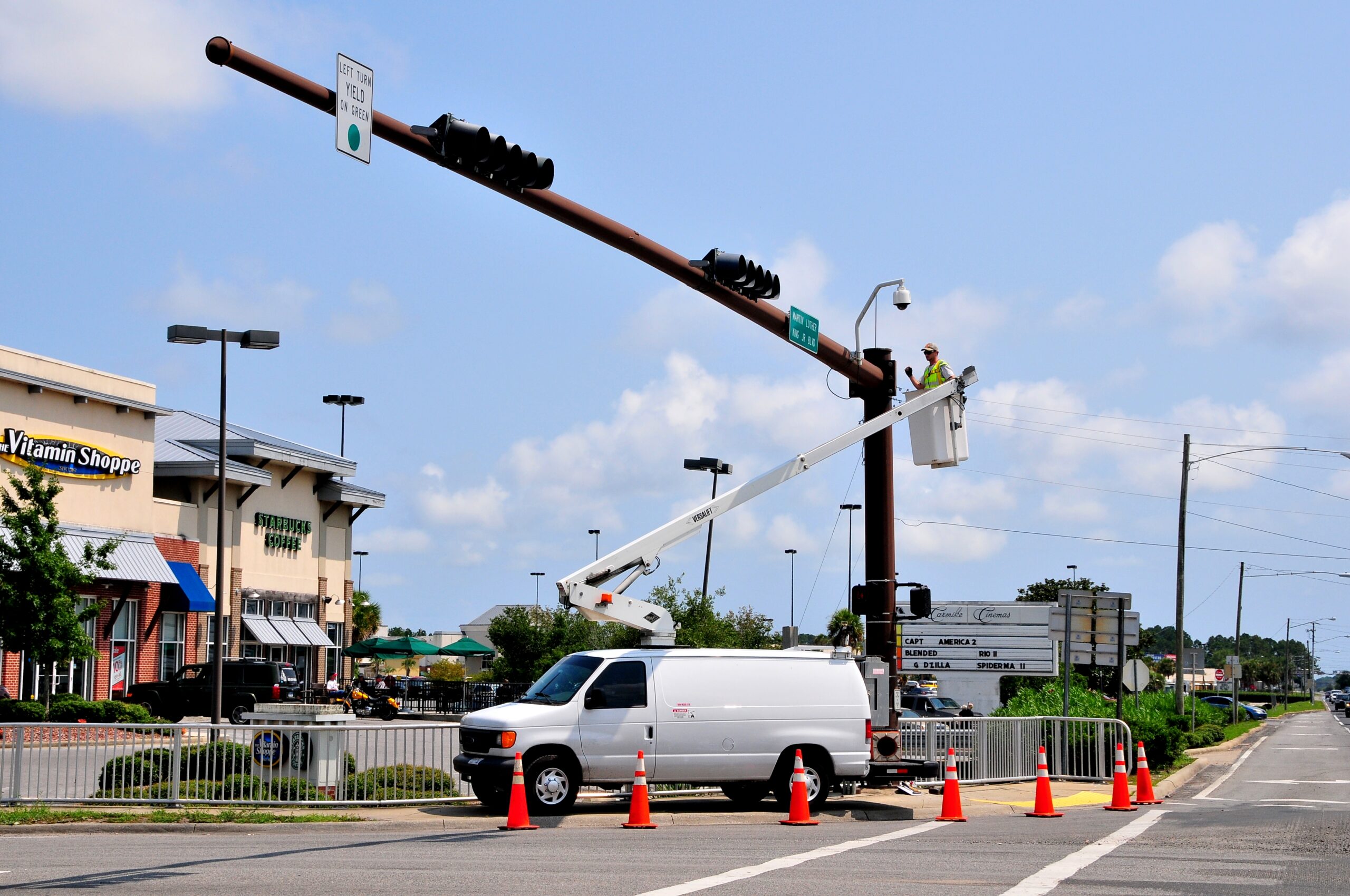 A worker in a lift repairs traffic lights near a shopping center