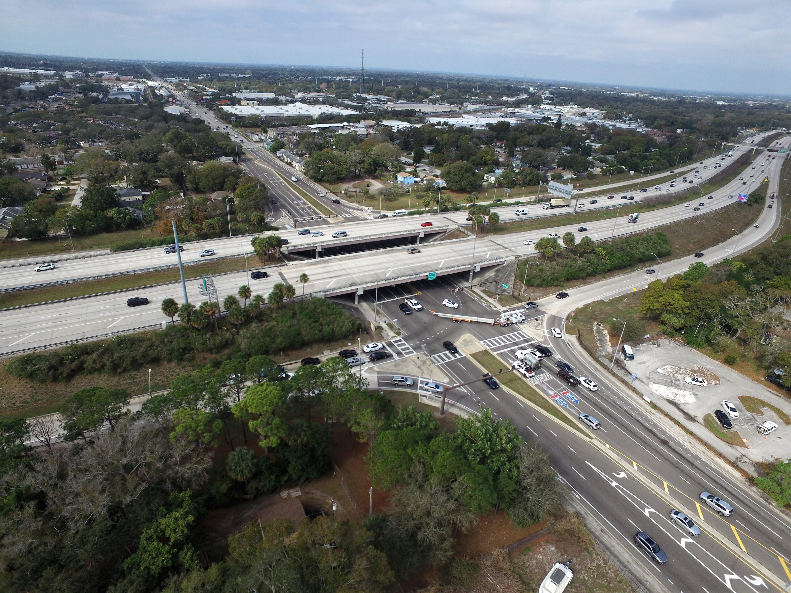 Aerial view of a busy highway interchange with surrounding greenery and urban area