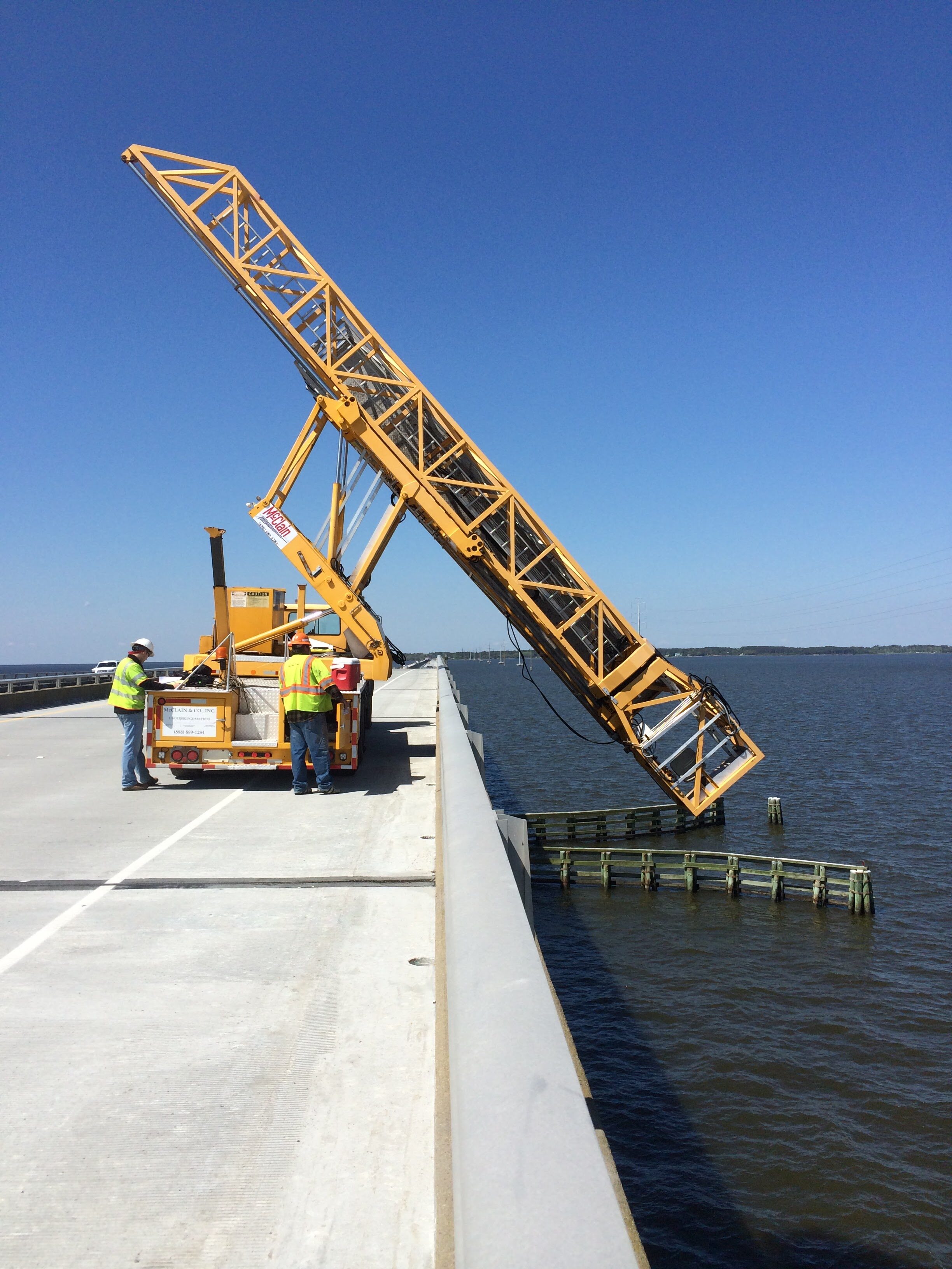 Construction workers operate a bridge inspection vehicle over water