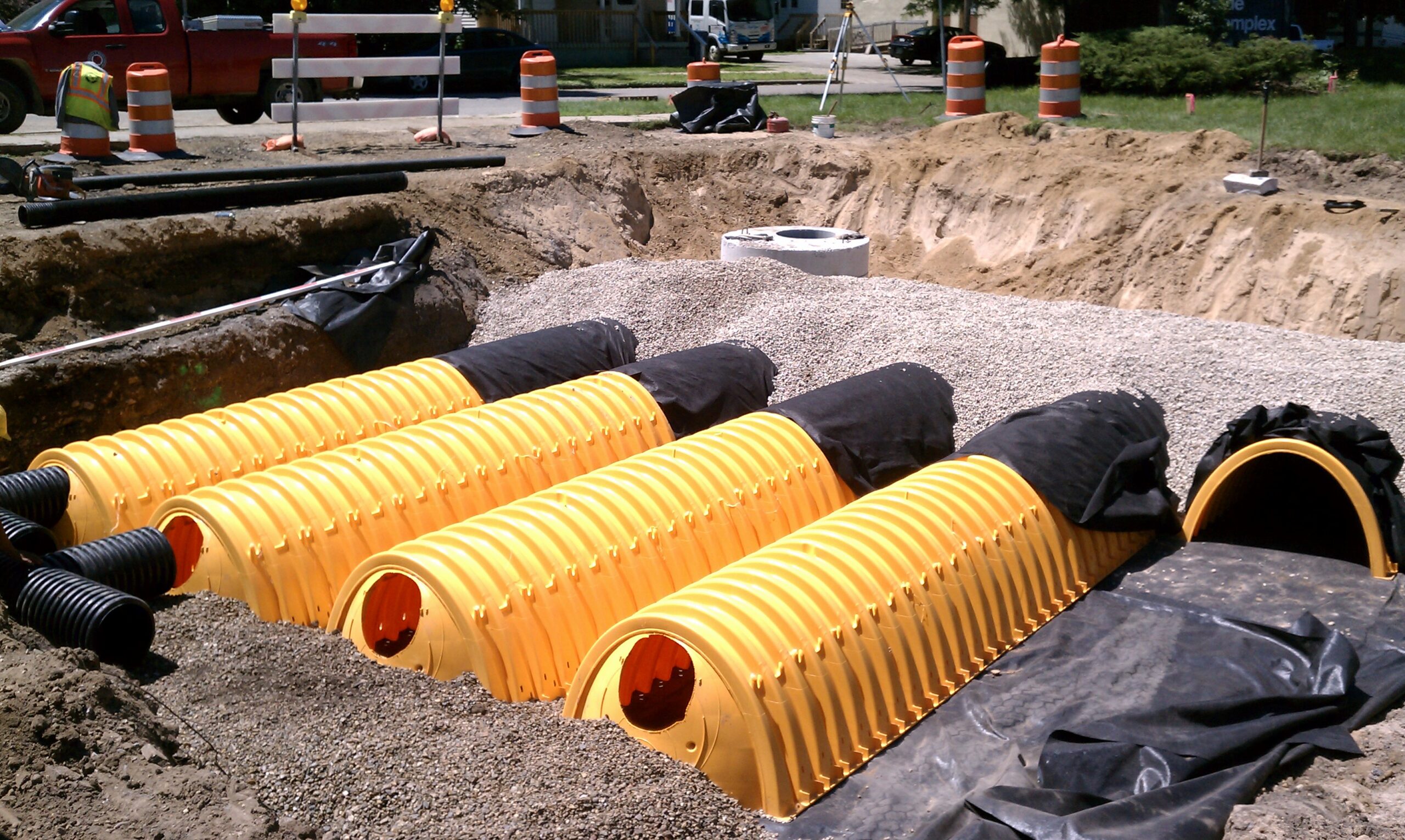Yellow stormwater detention system with gravel and construction equipment in urban setting