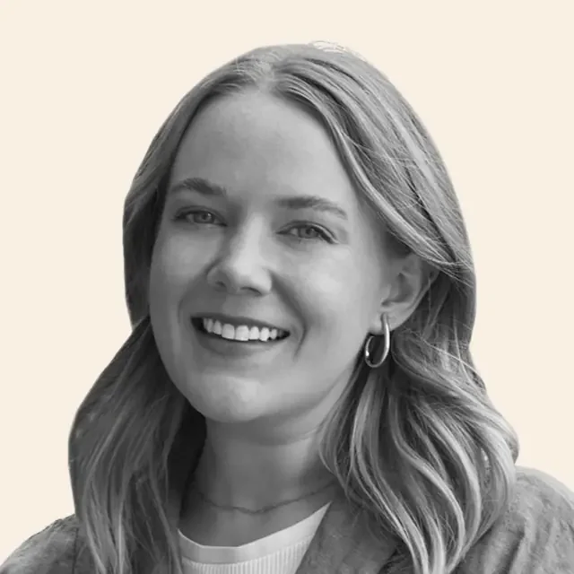 Kate smiling, wearing hoop earrings and a light jacket.