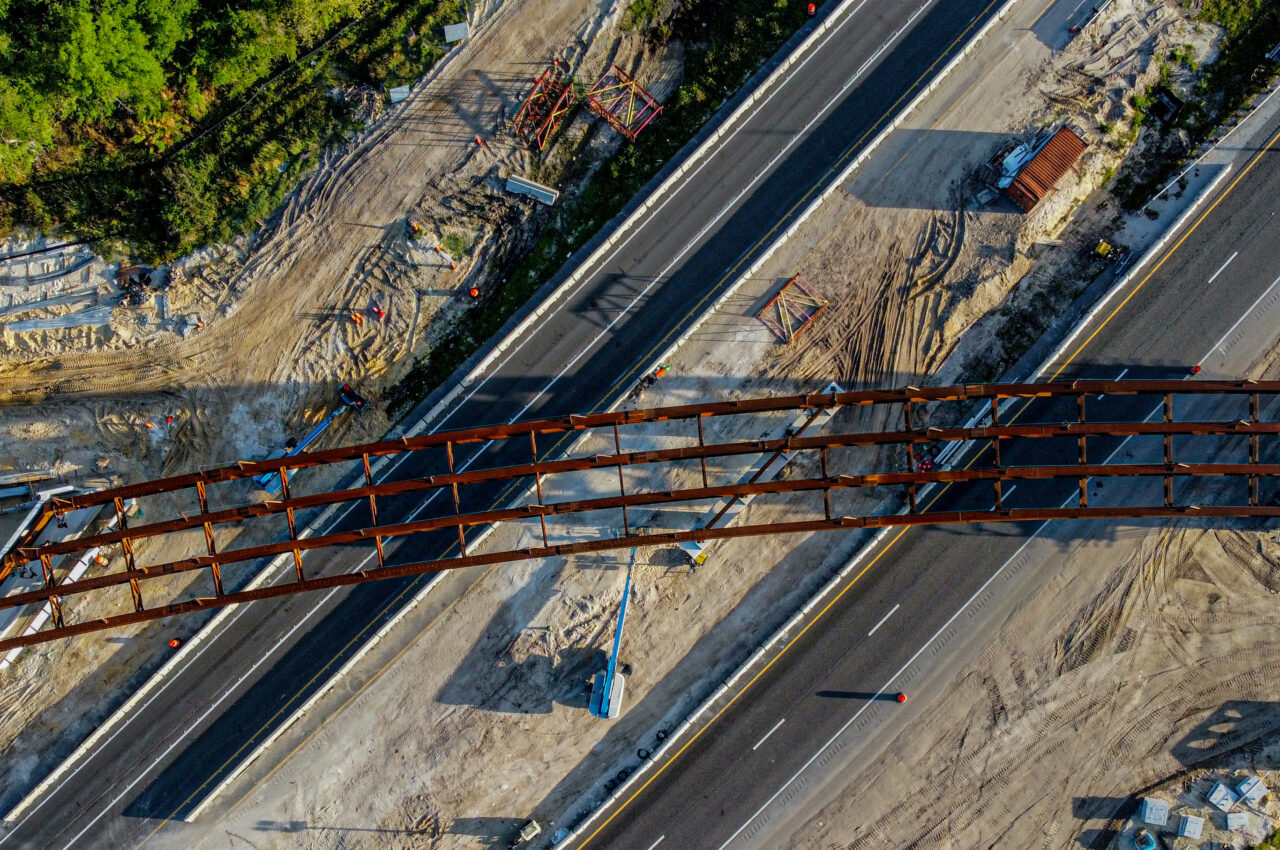 Aerial view of highway construction with a partially built bridge and surrounding earthwork