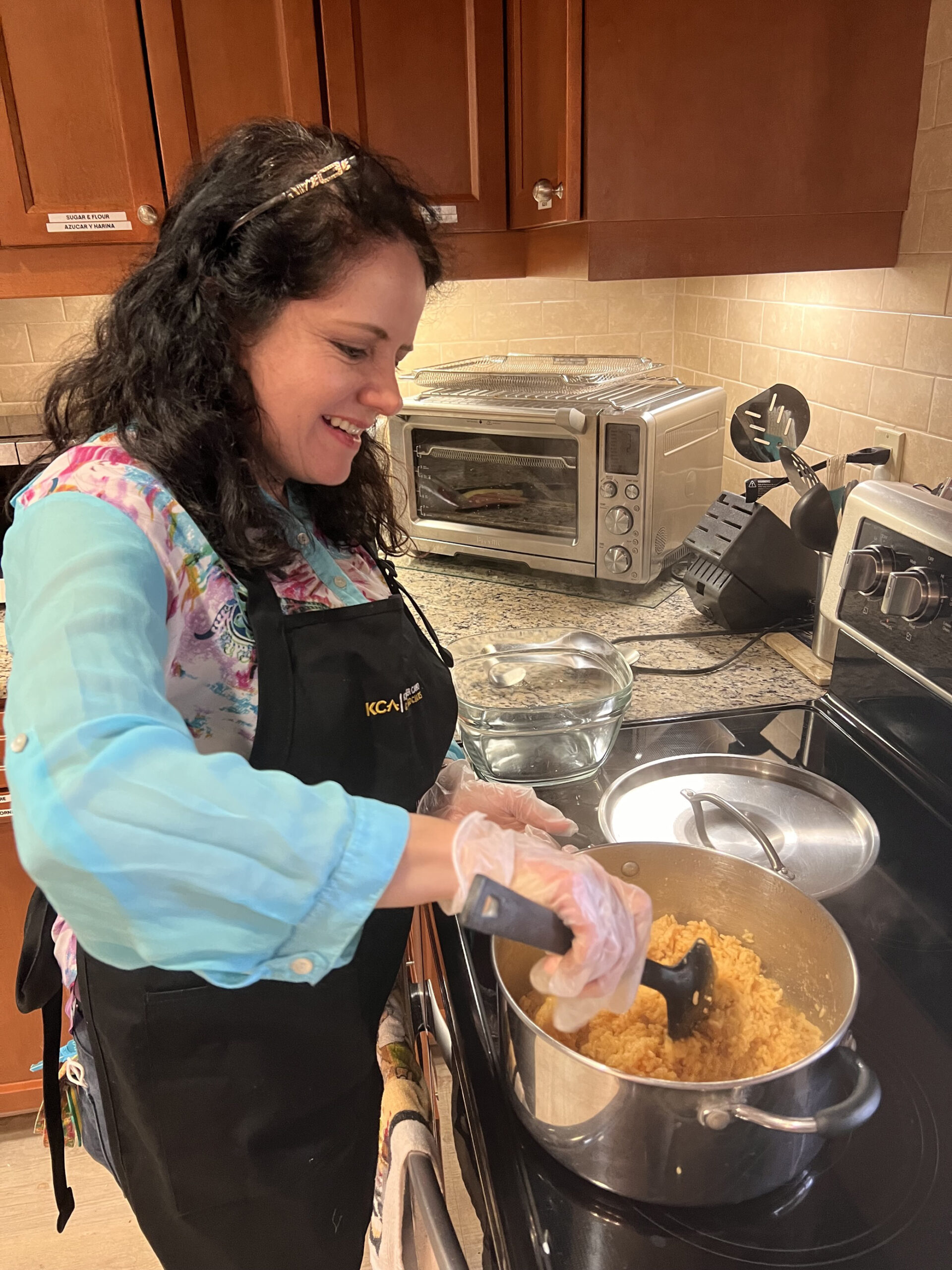 Diana smiling while stirring food in a large pot on a stove