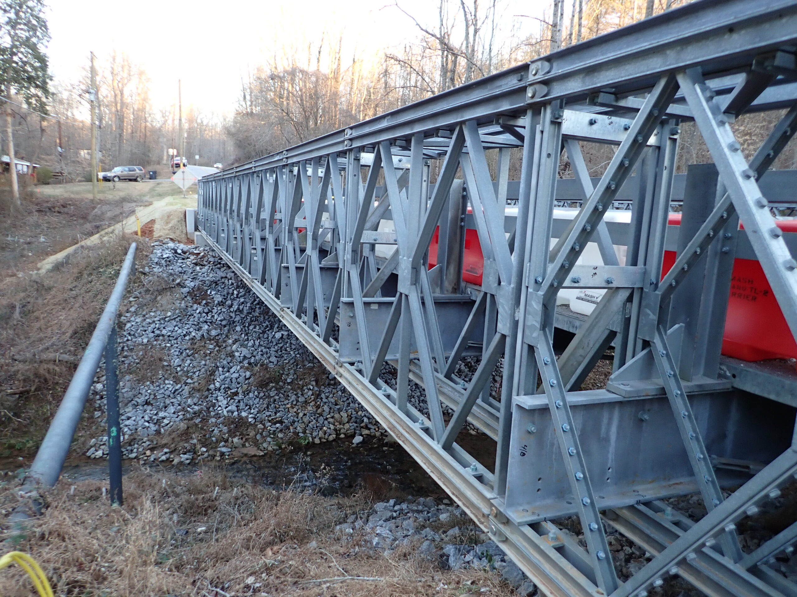 Metal bridge construction over rocky creek bed and rural road
