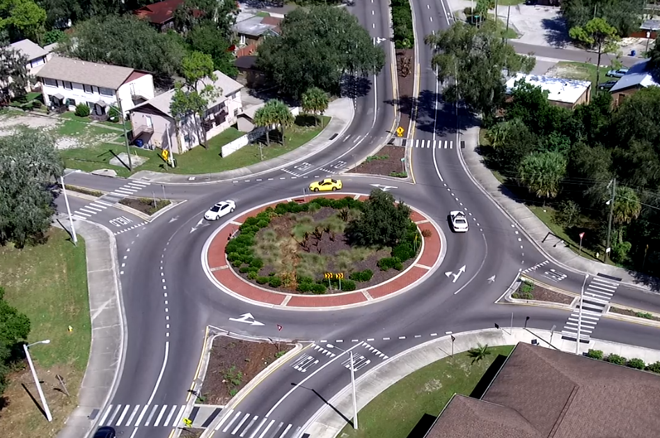 Aerial view of a roundabout with three cars, surrounded by vegetation