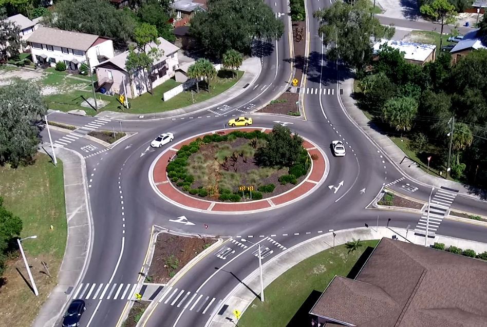Aerial view of a roundabout with three cars, surrounded by vegetation