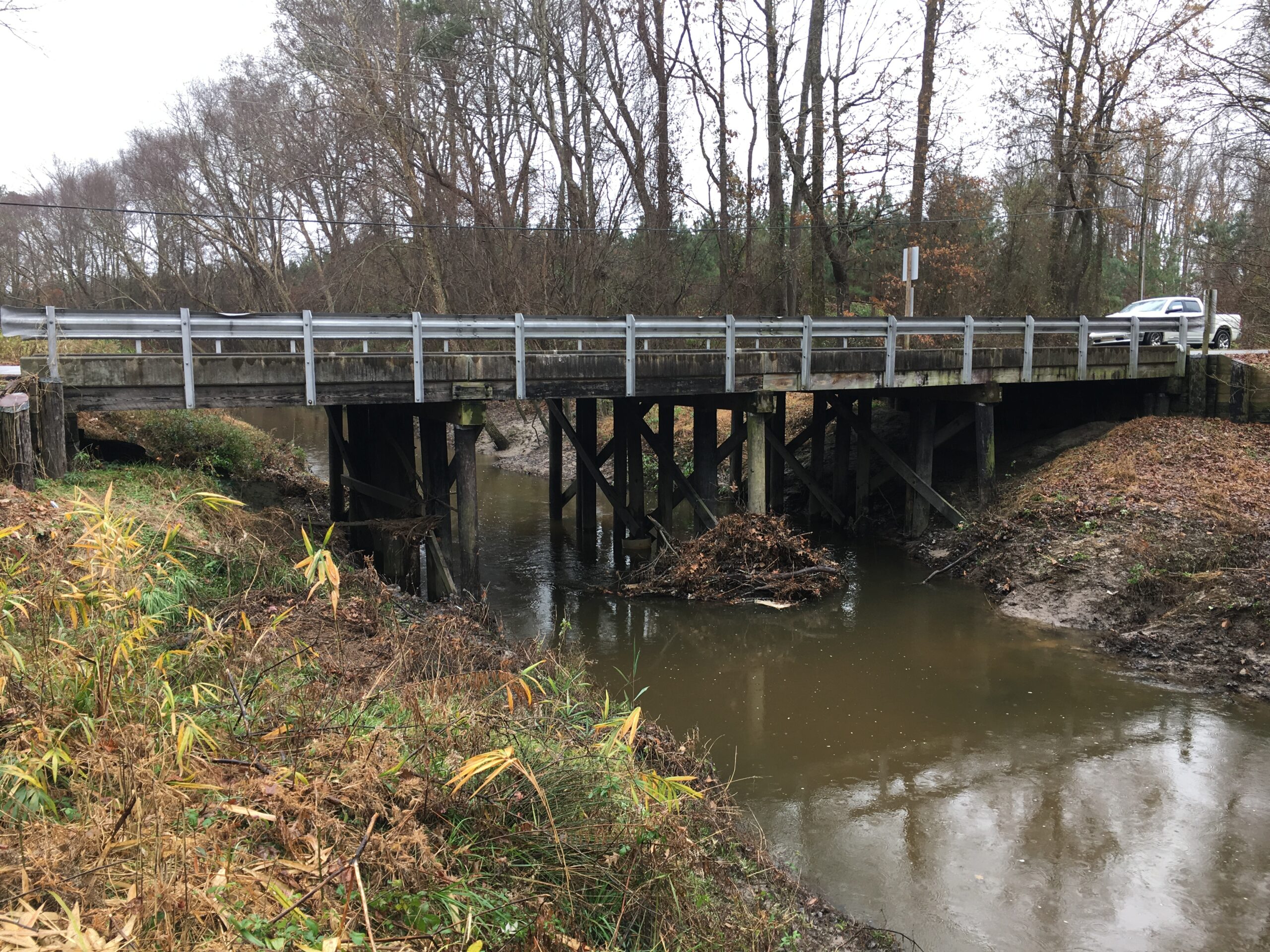 Wooden bridge over a creek surrounded by bare trees and shrubs