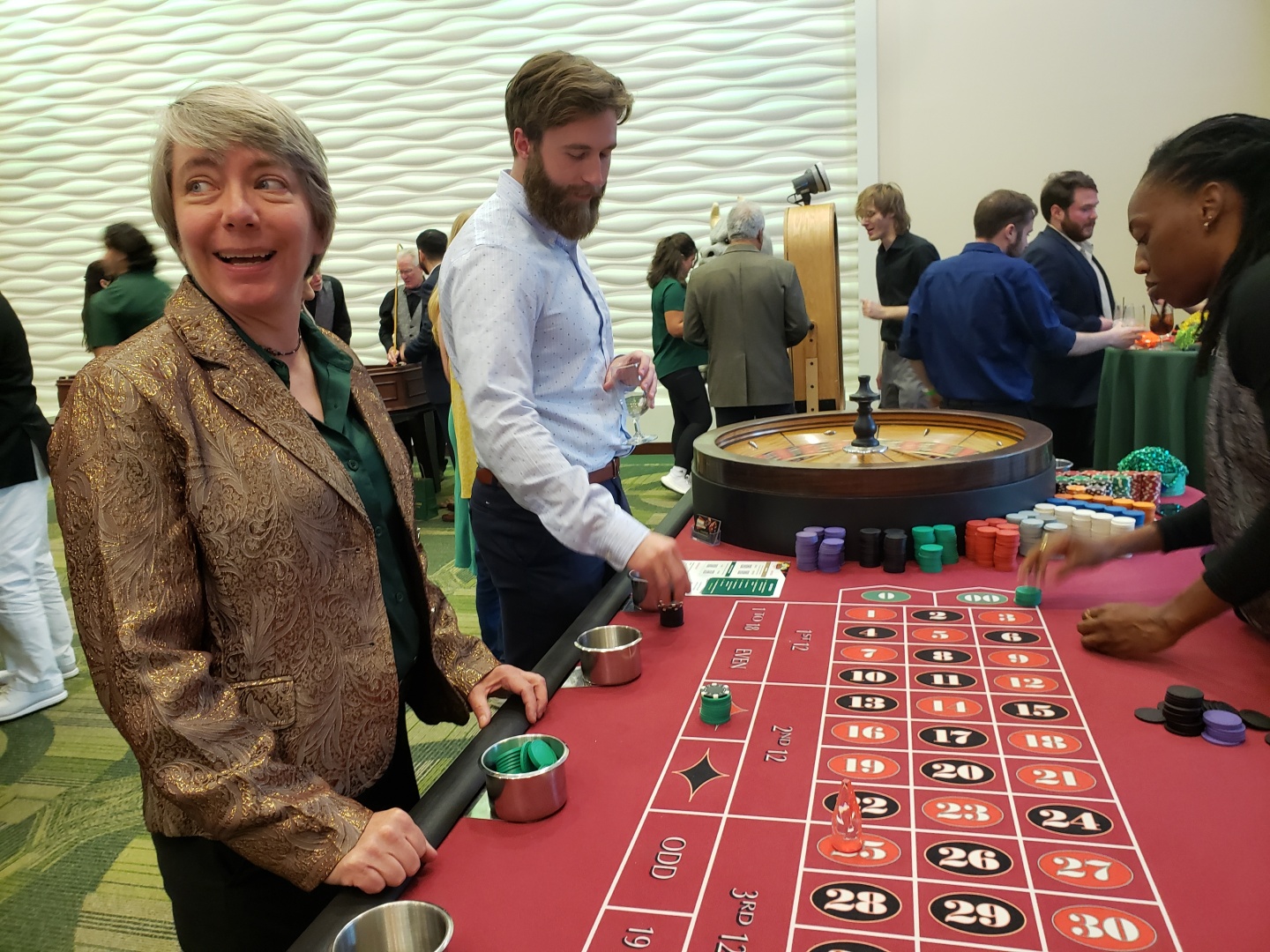 Bullarney24 interacting with a roulette table, smiling in a lively casino setting