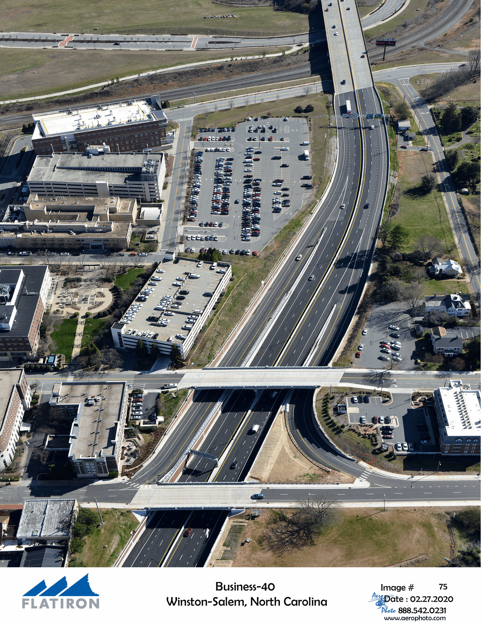 Aerial view of Business-40 highway in Winston-Salem, North Carolina, surrounded by buildings and parking lots. Flatiron logo at bottom left