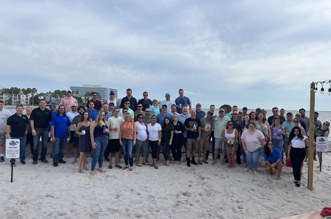 Group of people smiling on a sandy beach with a cloudy sky