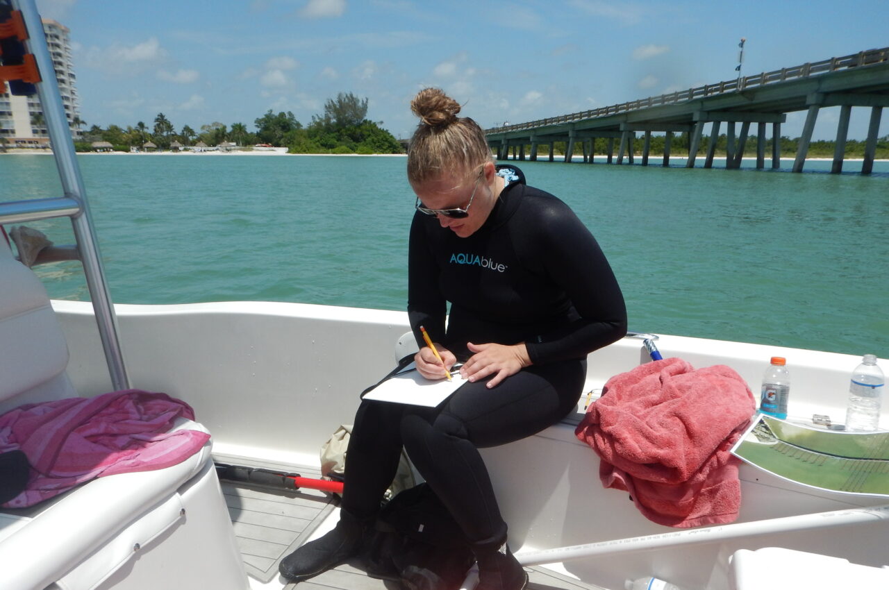 Catie conducting a seagrass survey on a boat in sunlight