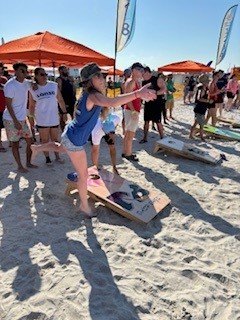 Person at corporate sports fest playing cornhole on sandy beach