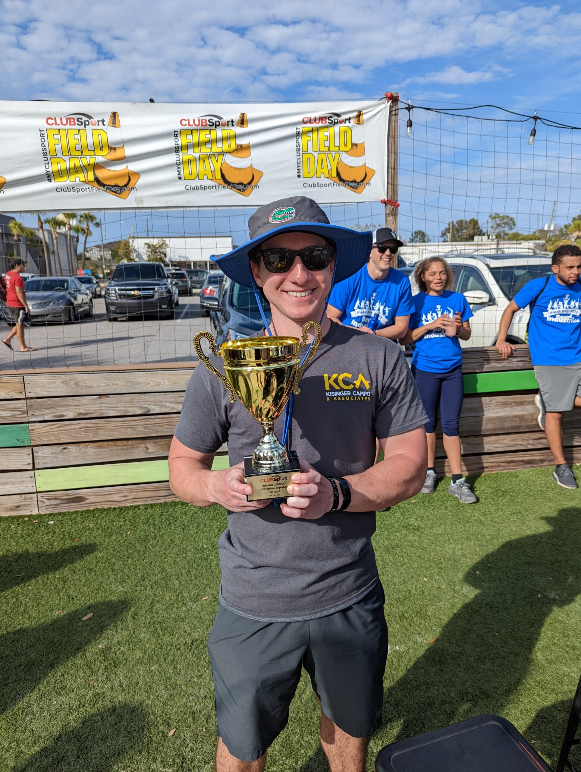 Man holding trophy at ClubSport Field Day event, smiling