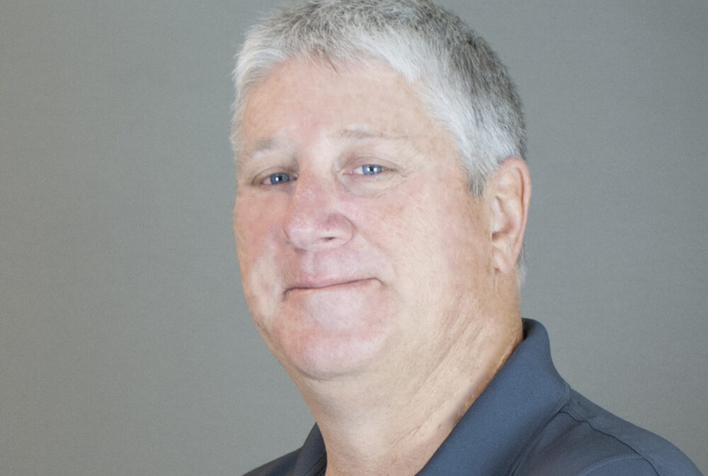 Sean Foley smiling, wearing a navy shirt with "KCA Kisinger Campo & Associates" logo