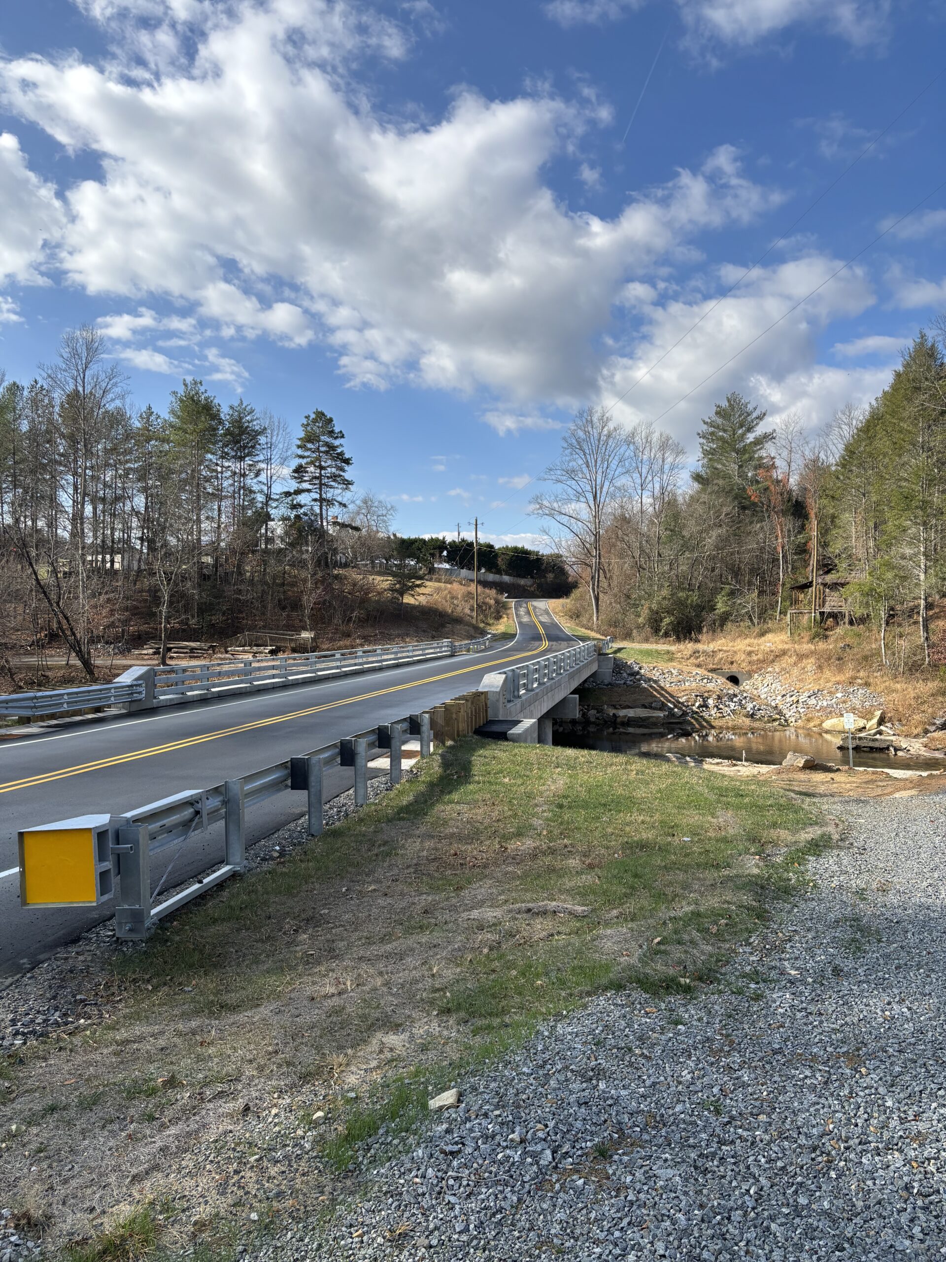 Sunny day with a bridge over a stream, surrounded by trees