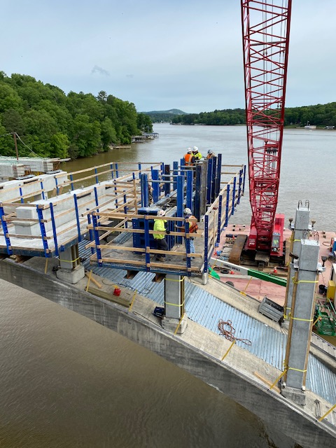 Construction workers building arch bridge over a river with crane