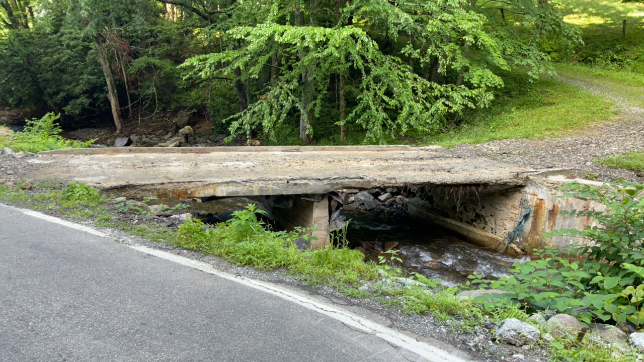 Weathered concrete bridge over a small creek surrounded by lush greenery