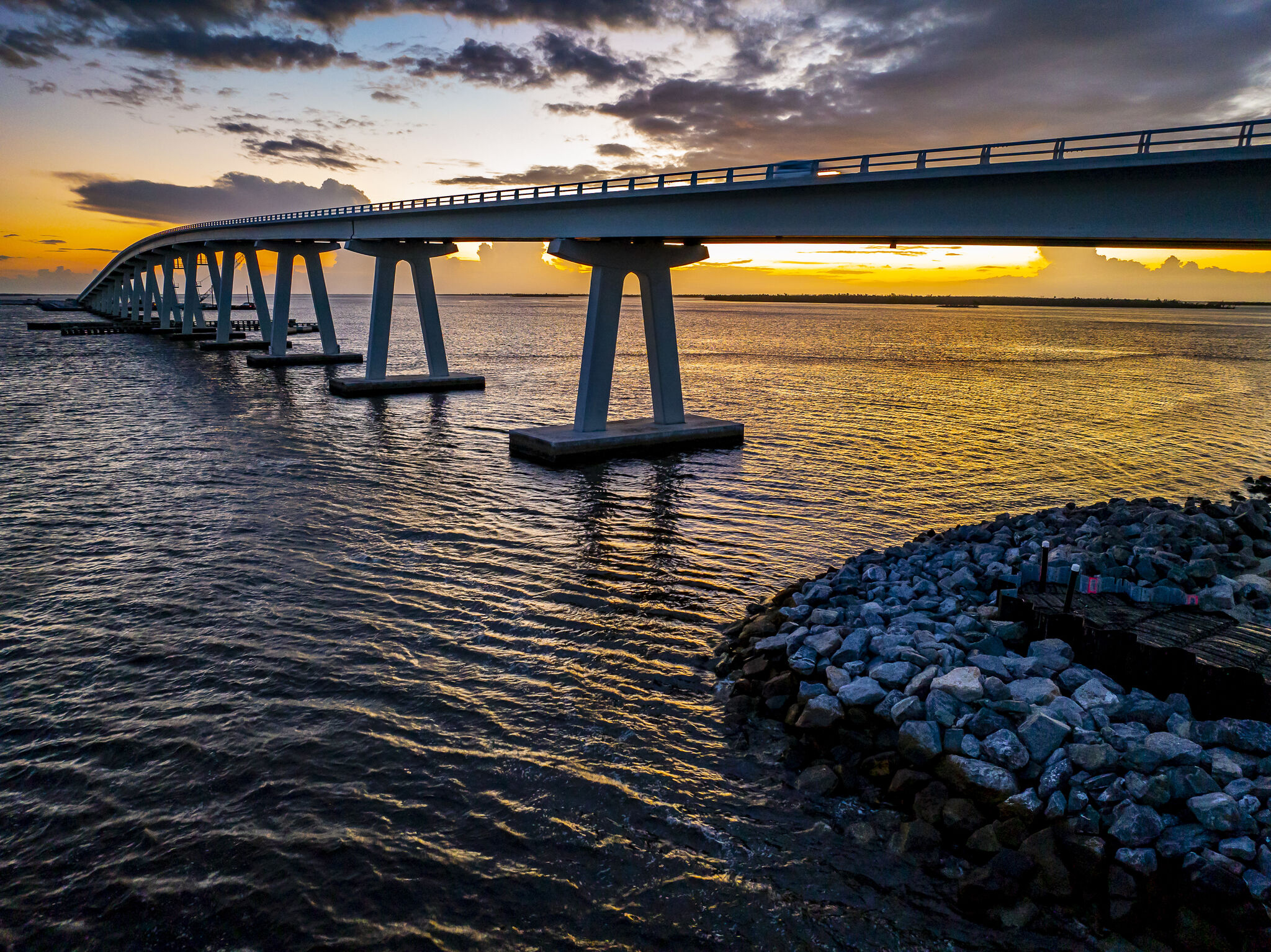 Bridge over water at sunset with cloudy sky