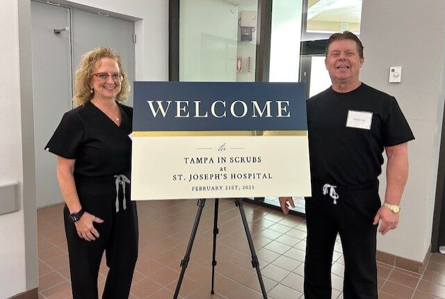 Tampa-in-Scrubs.jpg; two people in black scrubs smiling beside a "Welcome to Tampa In Scrubs at St. Joseph's Hospital, February 21st, 2023" sign