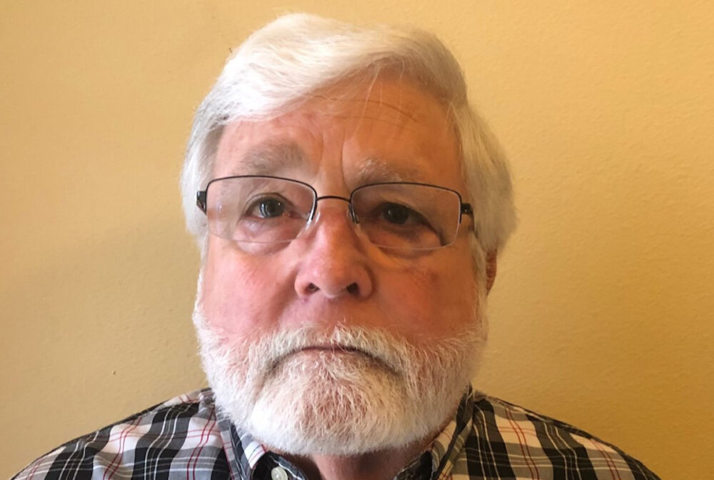 Timothy in glasses and plaid shirt, facing forward with a neutral expression