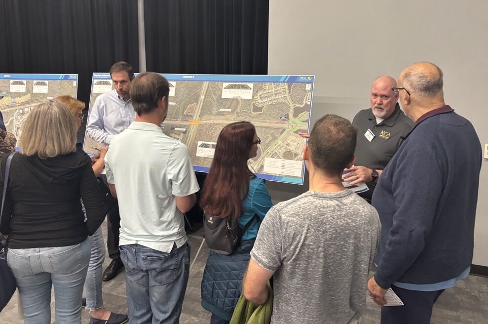 Seven people discussing road plans at a public meeting
