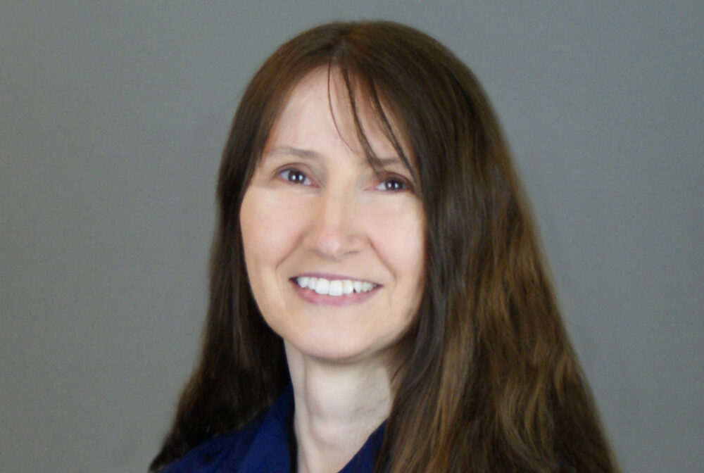 Trew-Donna smiling, wearing a blue shirt with long brown hair