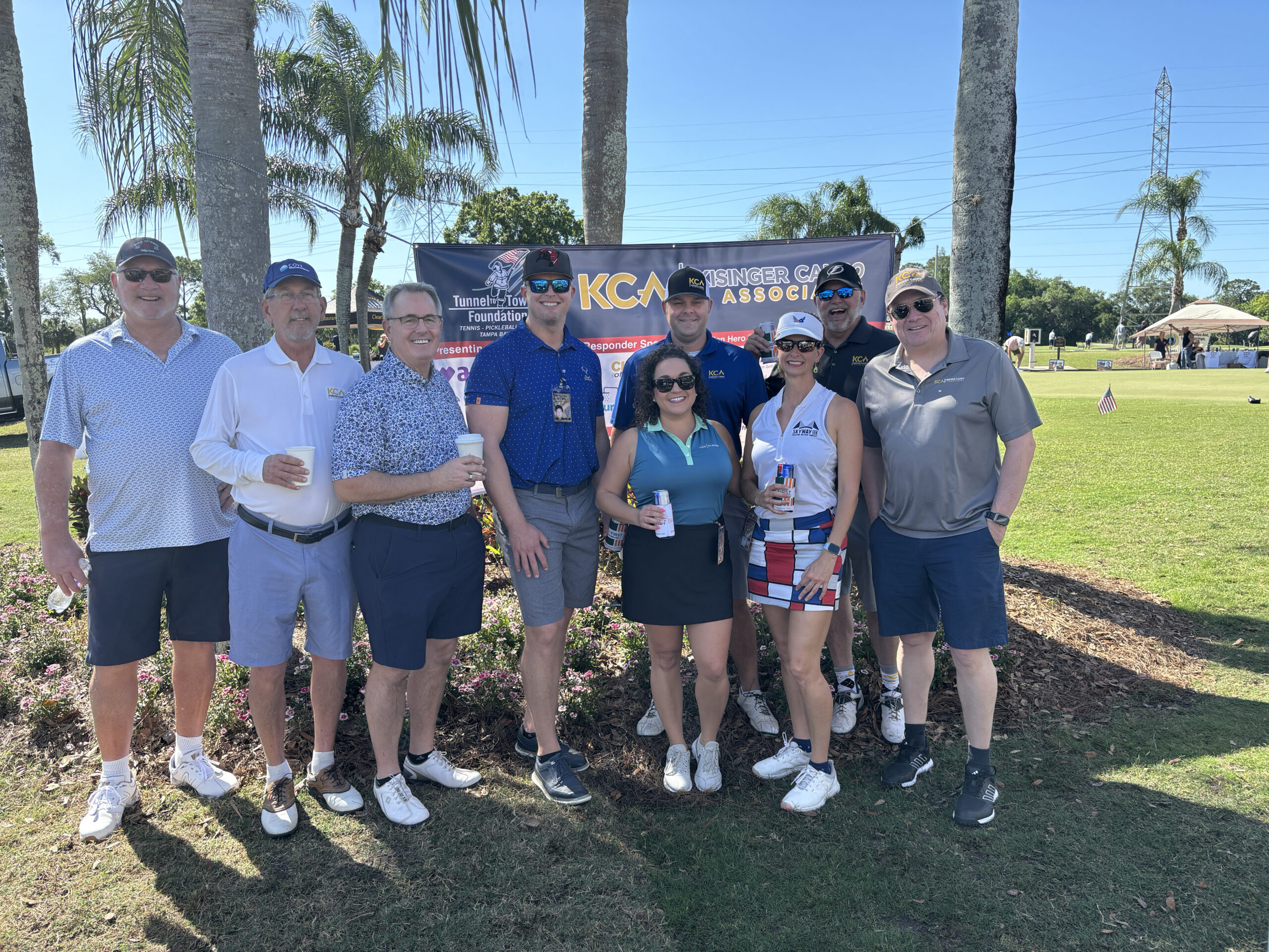 Group of smiling people at a golf event with Tunnels to Towers Foundation banner