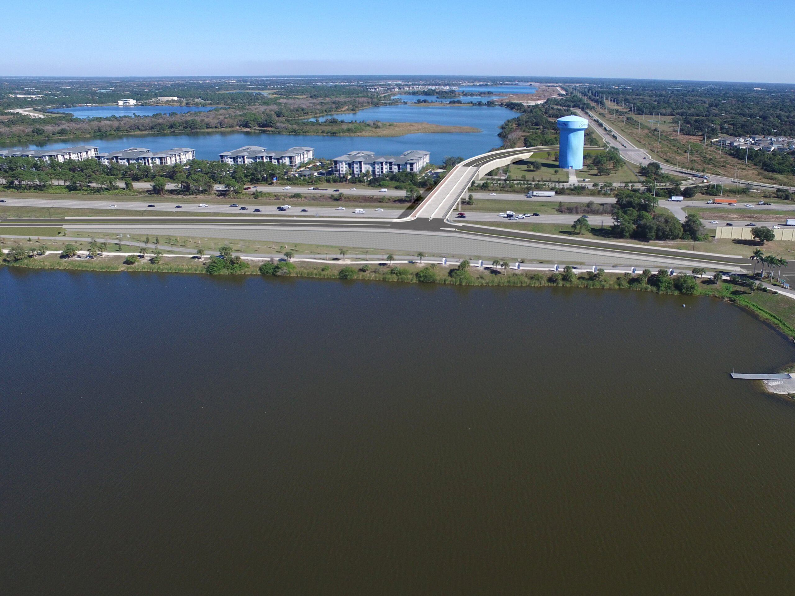 Aerial view of highway, water bodies, and residential area with a large blue water tower