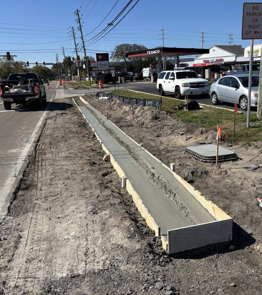 Newly poured concrete curb along busy road construction site