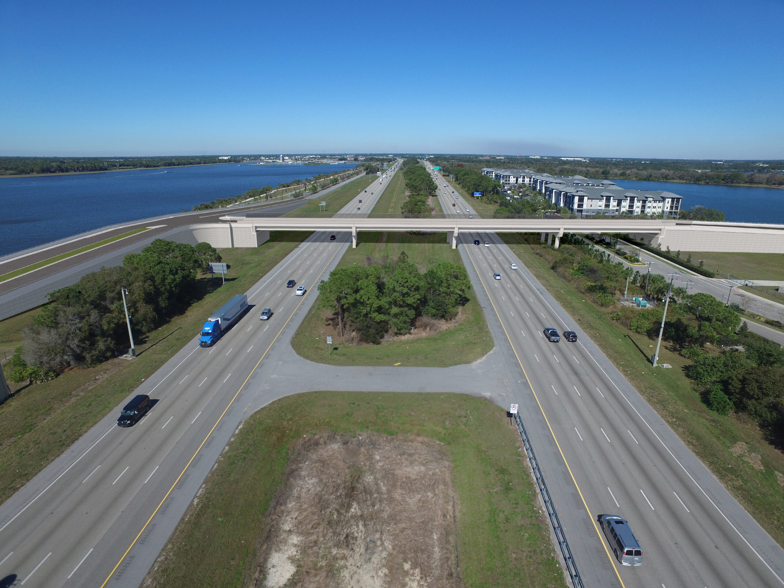 Highway intersection near water with vehicles and overpass, under clear sky