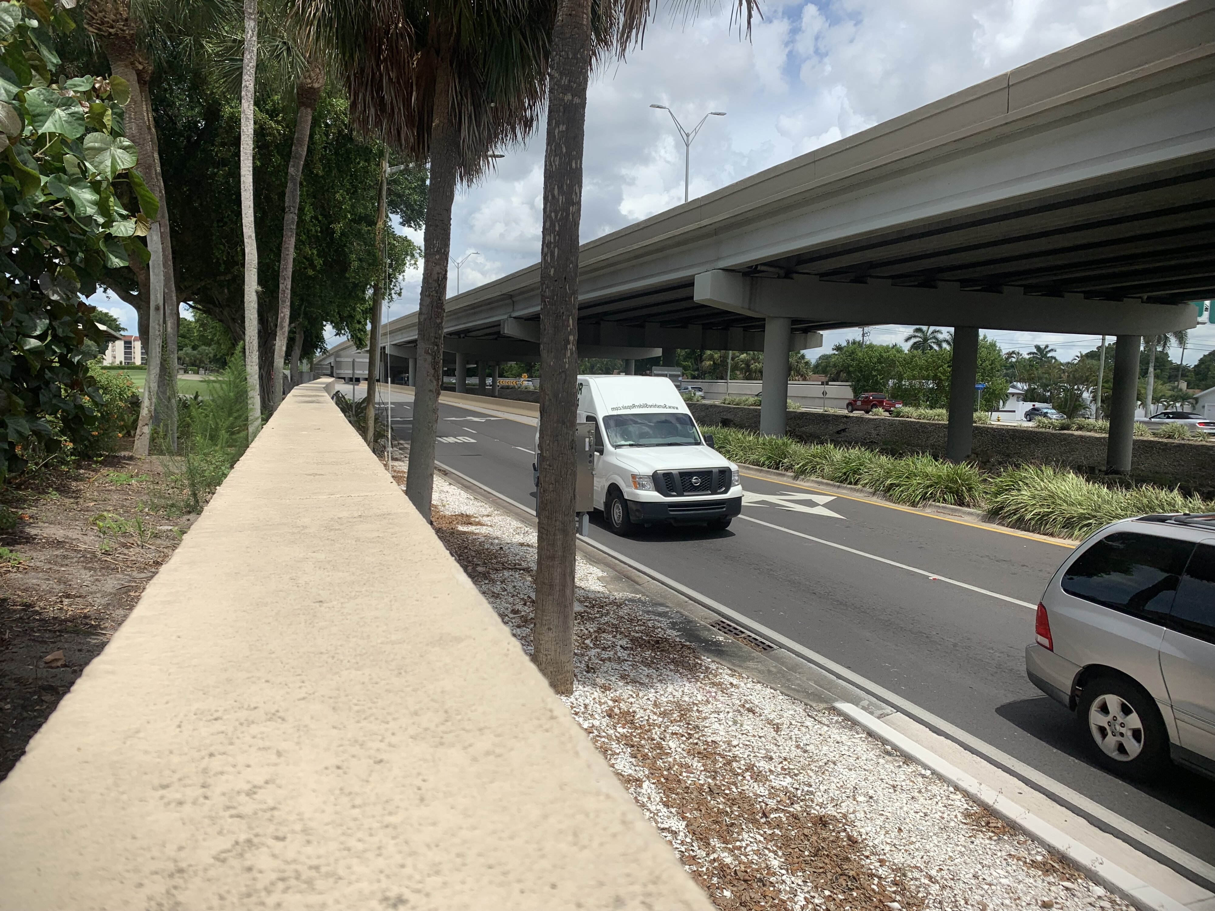 White van driving under Cape Coral Bridge on a sunny day