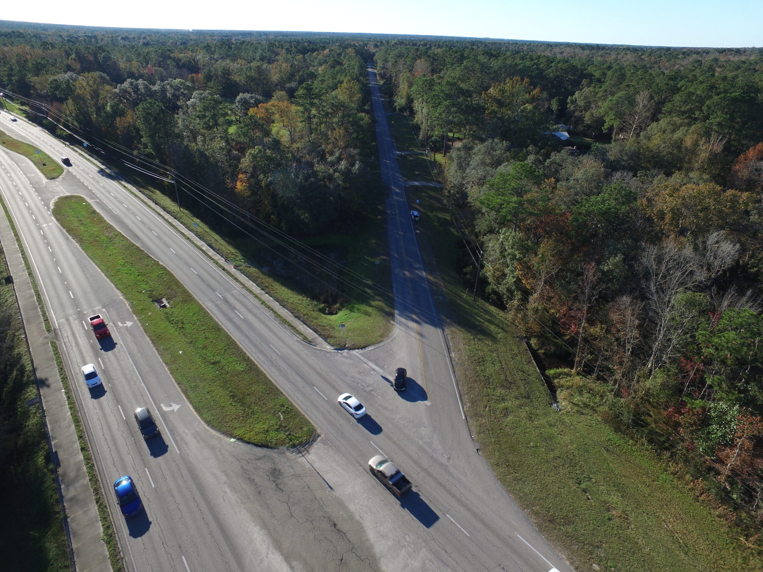 Aerial view of a highway intersection with several cars, surrounded by dense trees