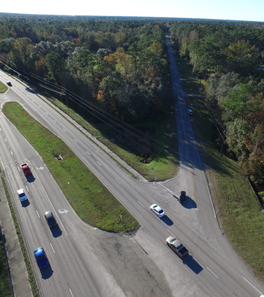 Aerial view of a rural three-way intersection with light traffic, surrounded by dense forest