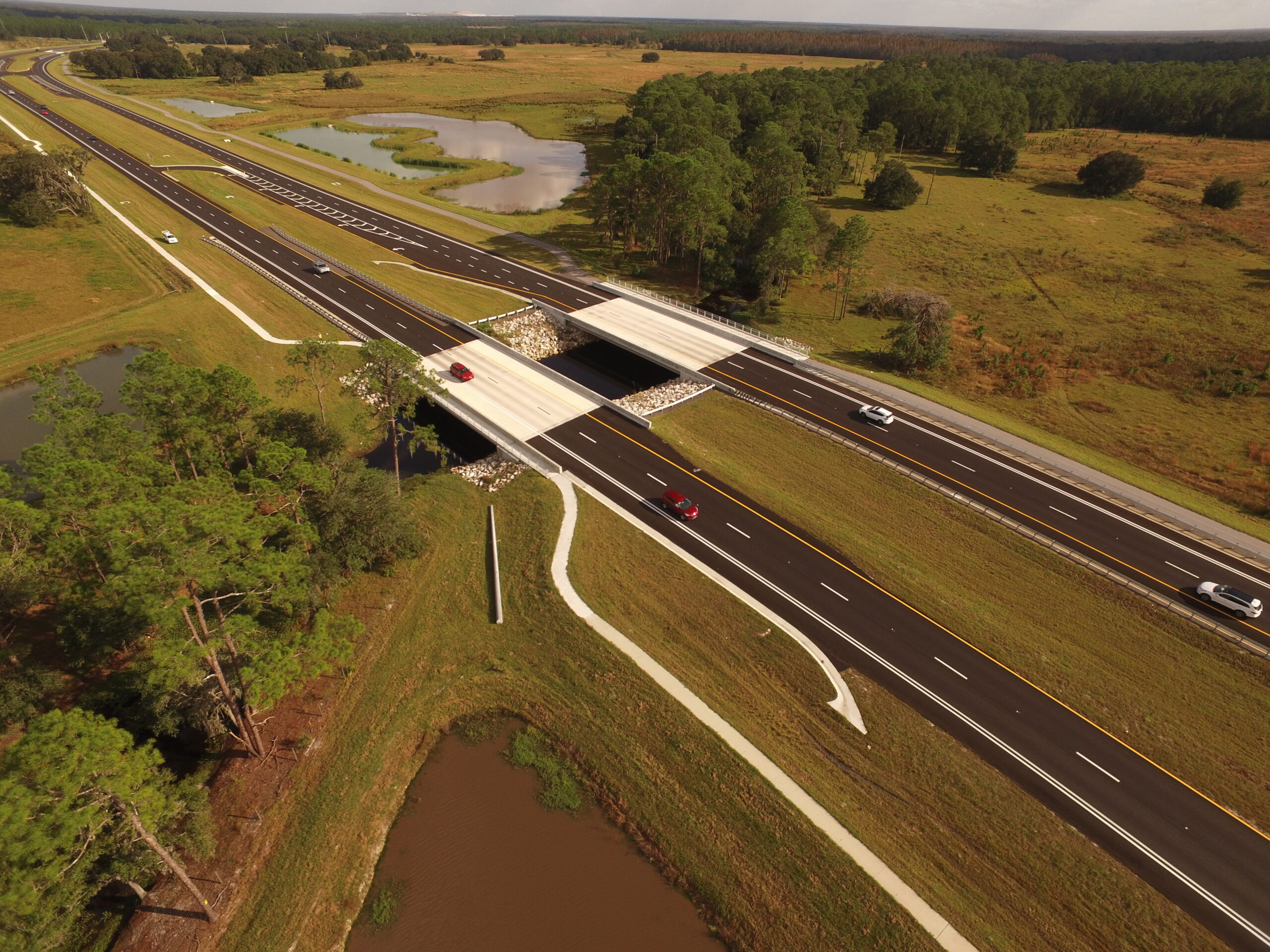 Aerial view of a highway overpass with surrounding grassy landscape and ponds