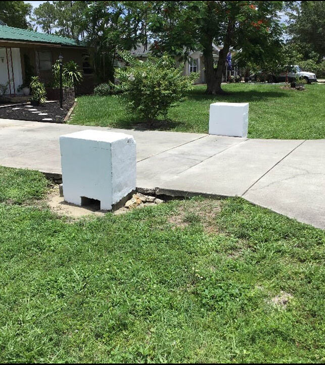 Concrete blocks partially obstruct a driveway in a suburban yard