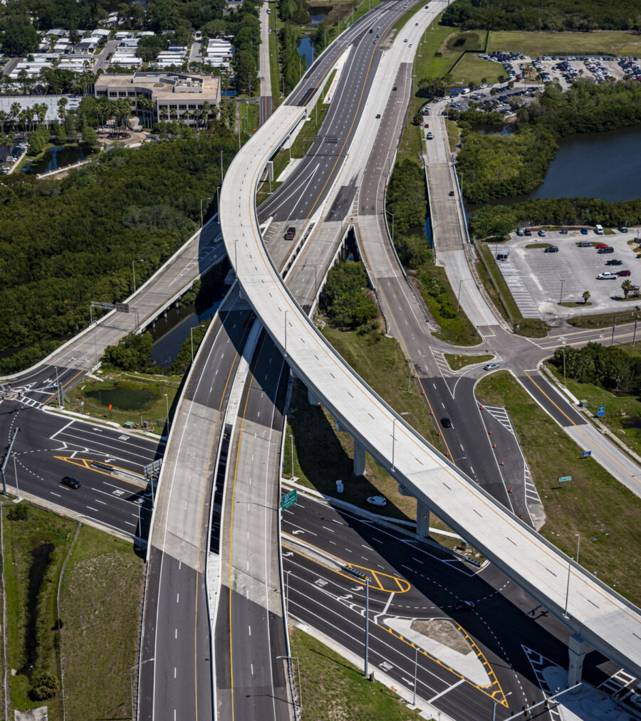 Aerial view of a multi-level highway interchange with surrounding greenery and nearby parking lots