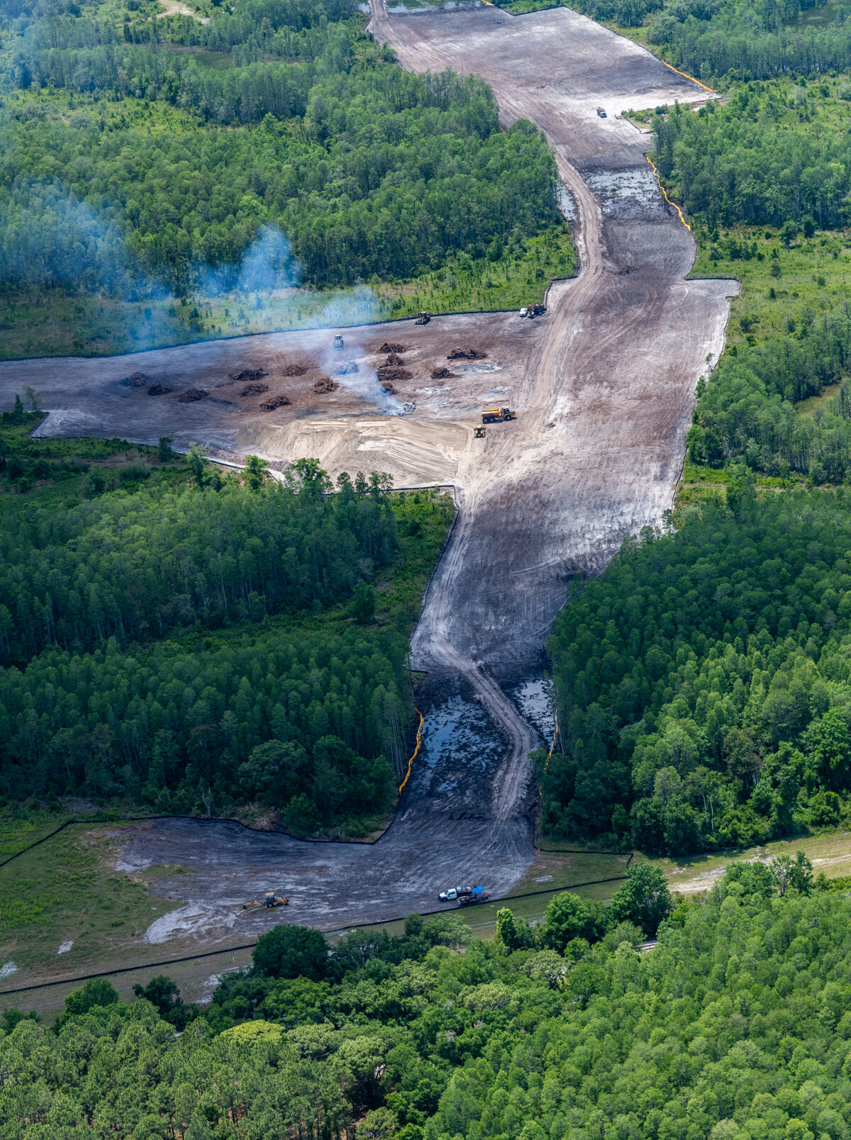 Construction site clearing through dense forest, aerial view