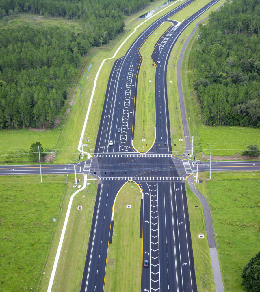 Aerial view of a multi-lane highway intersection surrounded by green forest and grassland
