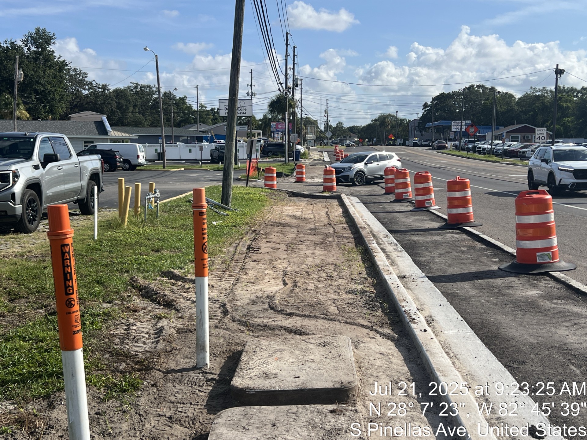 Construction site on South Pinellas Avenue with traffic cones and utility warning markers. Date and coordinates displayed