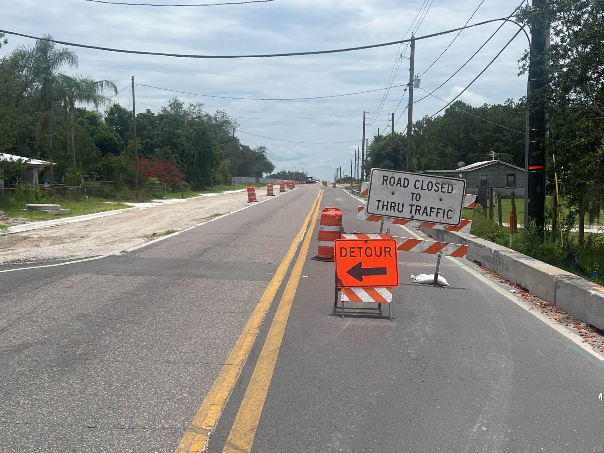 Road closed sign and detour with orange barrels on Turkey Creek Road