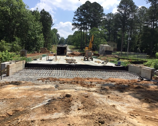 Bridge under construction in a rural area with trees and machinery