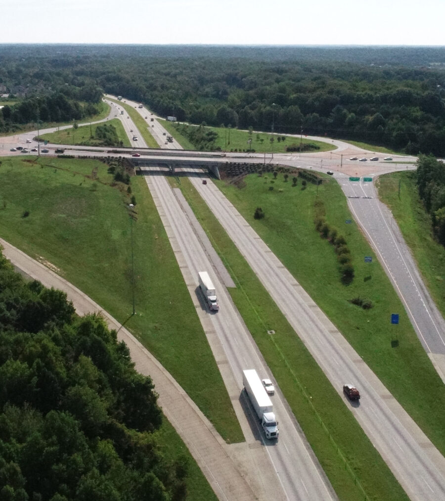 Overhead view of highway intersection with trucks and green landscape