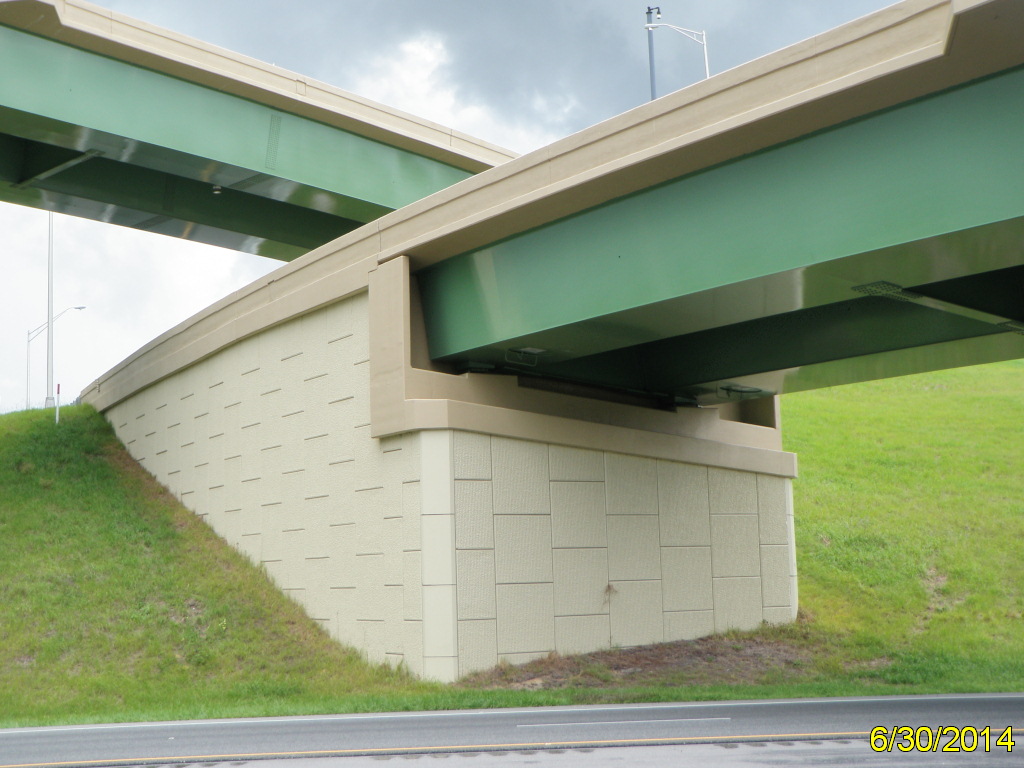 Green bridge with beige concrete support over grassy slope, date marking 6/30/2014