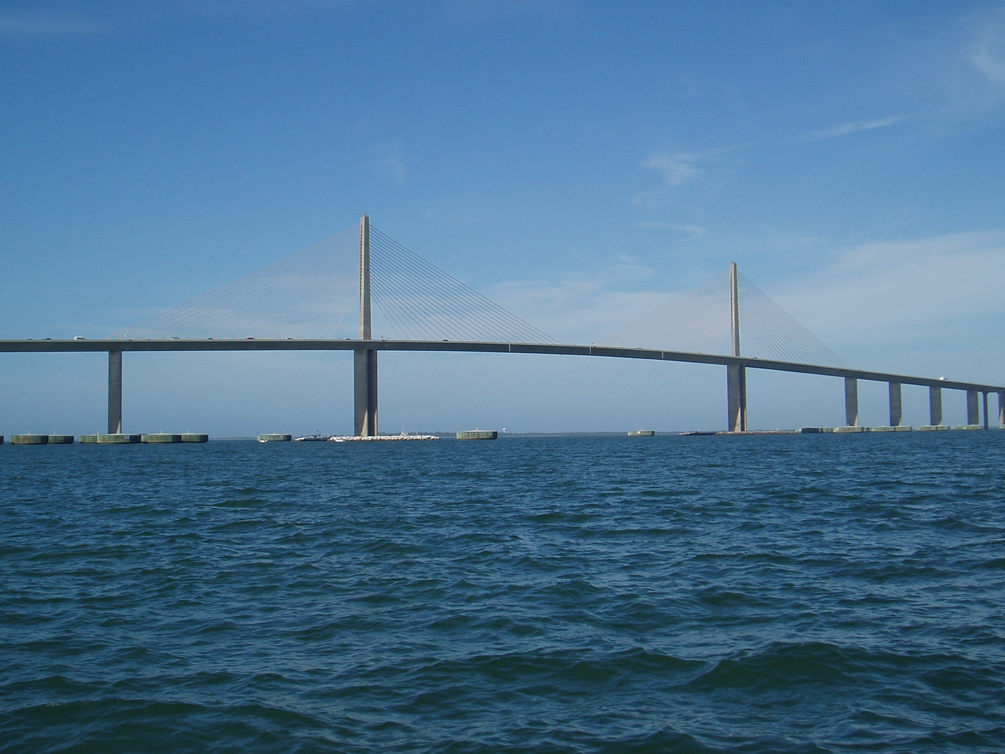 Suspension bridge over blue water with clear sky above
