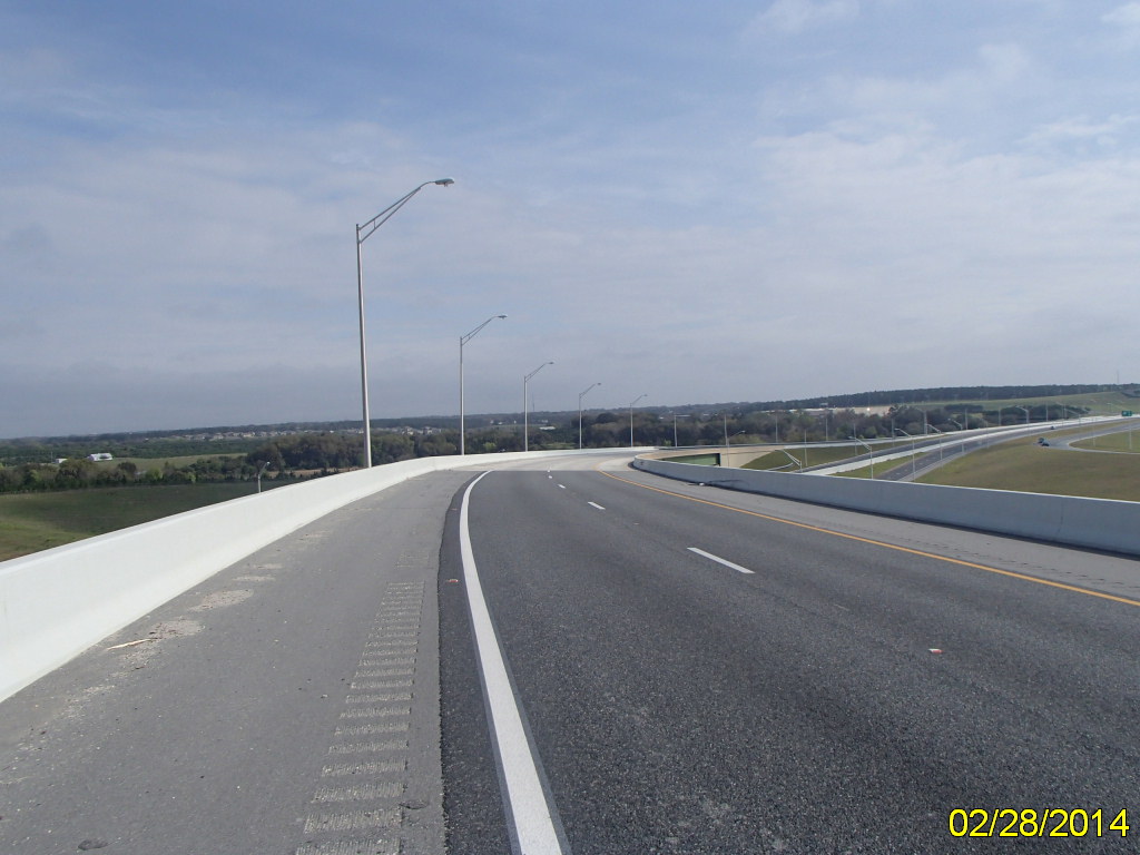 Empty highway curving through countryside under cloudy sky, dated February 28, 2014