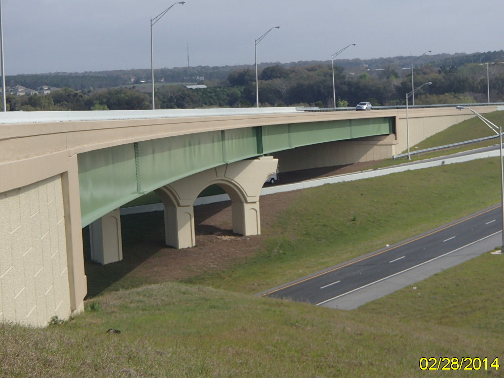 Elevated highway with green beams above grassy slope and road